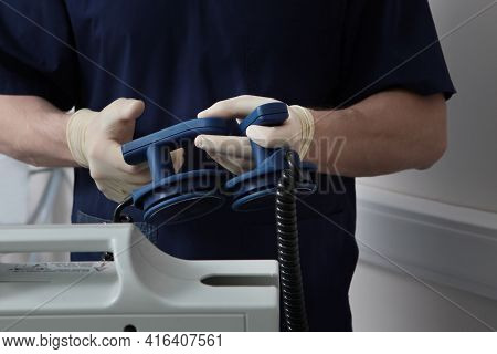 Resuscitation In The Clinic. Preparing For Defibrillation. In The Hands Of The Resuscitator, He Hold
