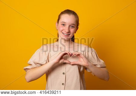 Be My Valnetine. Charming Young Girl Confesses In Love, Shows Heart Gesture, Smiles Broadly, Has Rom