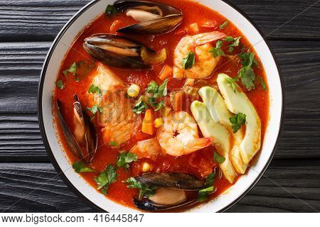 Rich Soup With Seafood, Vegetables And Avocado Close-up In A Bowl On The Table. Horizontal Top View 