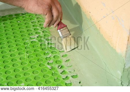 Worker Applies Waterproofing With A Small Brush