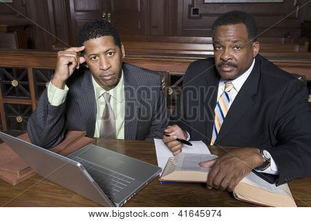 ภาพเหมือนของนักธุรกิจและทนายนั่งกันใน courtroom