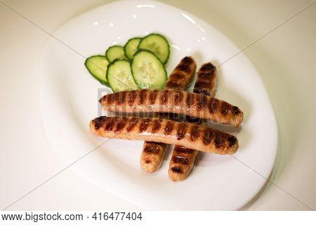 Grilled Meat Sausages For Hot Dog, Kupaty, Fatty Food Cooked On The Barbecue, With Fresh Vegetables 