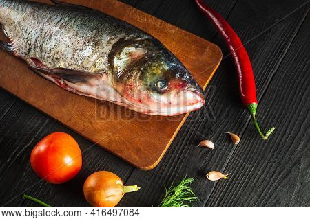Hypophthalmichthys Or Bighead Carp On A Cutting Board With Vegetables Before Cooking. Raw Peeled Fis