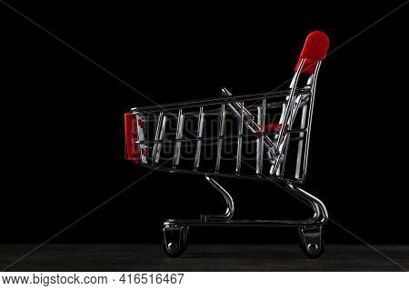 Dark Background Image With An Empty Toy Shopping Cart.  A Concept Image For Economic Downturn, Reces