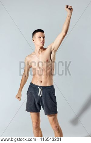 Sport Man In Shorts Doing Exercise Leaning Forward On Gray Background Cropped View