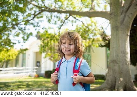 Child With Rucksacks Standing In The Park Near School. Pupils With Books And Backpacks Outdoors. Kid
