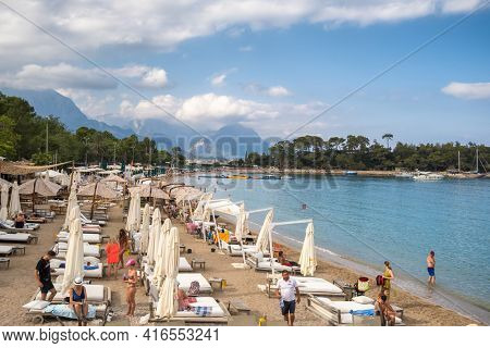 Kemer, Turkey - October 14, 2020: Deck chairs on the beach with umbrellas and loungers with mountains at background in Kemer, Antalya, Turkey