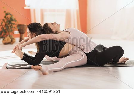 Two Women Doing Upavishta Konasana And Baddha Konasana Bends Sitting On A Mat In A Yoga Studio, Pers