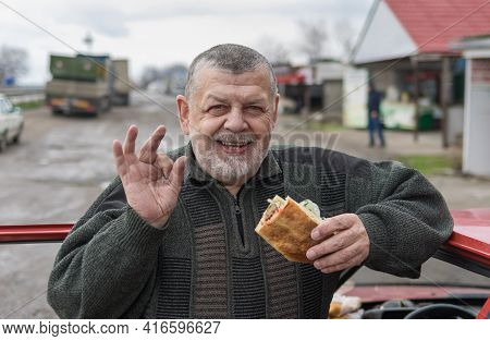 Portrait Of Positive And Happy Caucasian Senior Driver Holding Lyulya Kebab In Lavash Leaning His El