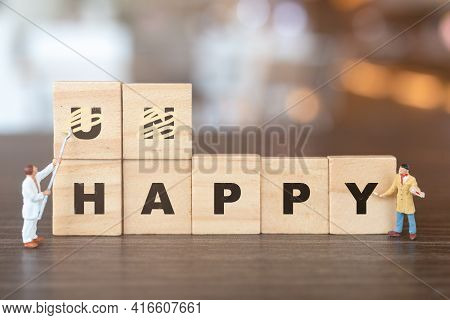 Worker Team On Unhappy Word In Wooden Alphabet Letters With Prefix Un Crossed Out, Leaving The Word