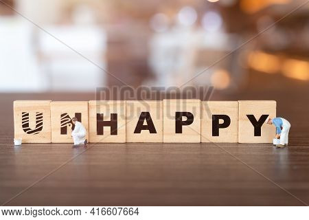 Worker Team On Unhappy Word In Wooden Alphabet Letters With Prefix Un Crossed Out, Leaving The Word