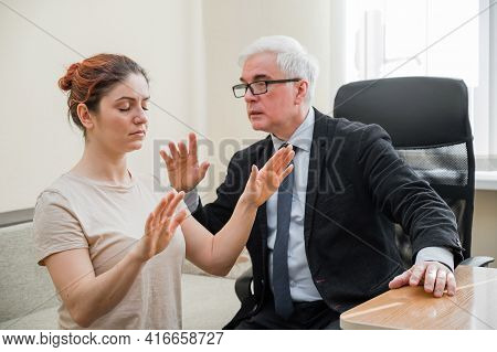 Mature Gray-haired Man Hypnotizes Caucasian Woman During Hypnotherapy Session. The Psychologist Uses