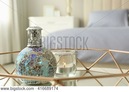 Closeup View Of Stylish Catalytic Lamp With Burning Candle On Tray In Bedroom, Space For Text. Cozy 