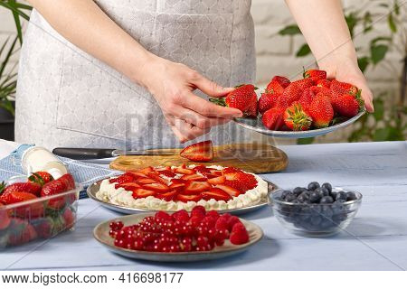 Woman Baker Stacks Strawberries On Meringue Strawberry Cake Base. Homemade Strawberries Cake Made Fr