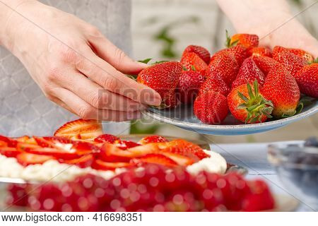 Woman Baker Stacks Strawberries On Meringue Strawberry Cake Base. Homemade Strawberries Cake Made Fr