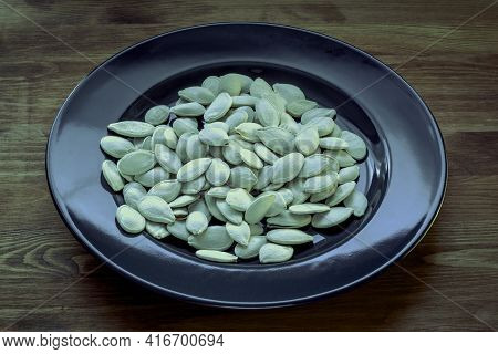 Pumpkin Seeds On A Wooden Table. Quality Photo