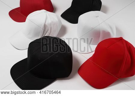 Many Baseball Snapback Hats In Different Colors Black, White And Red Laid Out Isolated On White Surf