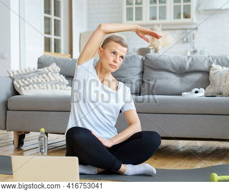 Senior Woman Stretching Hand, Online Training With Laptop In Living Room. Exercise For Well-being, W
