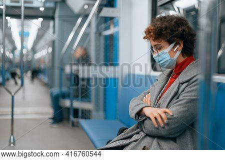Tired Woman In A Protective Mask Sleeps In An Empty Subway Car .