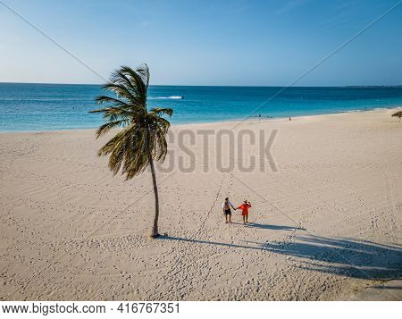 Eagle Beach Aruba, Palm Trees On The Shoreline Of Eagle Beach In Aruba, Couple Man, And Woman On The