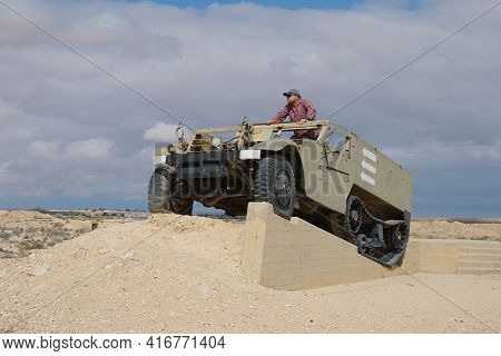 A Man In A Baseball Cap And Dark Glasses In An Old Military Vehicle