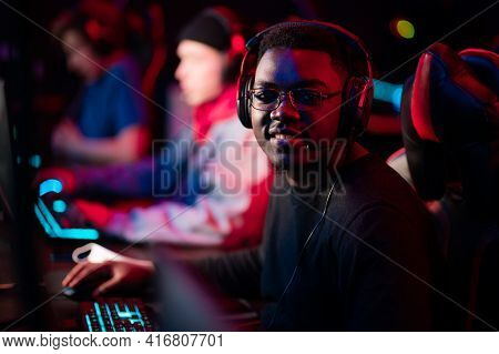 Neon Light In The Arena At The Online Shooter Tournament. A Young Black Cyber Athlete Looks At The C