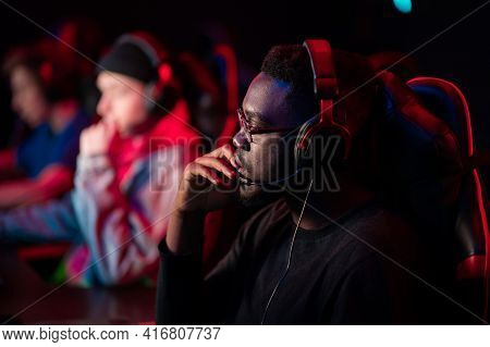 A Close-up Portrait Of A Handsome Dark-skinned Man Wearing Glasses And A Headset In Front Of A Compu