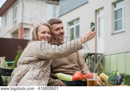 Selfies On A Smartphone For Social Networks Are Made By A Girl And A Guy Sitting At A Picnic Table I