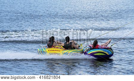 Mackay, Queensland, Australia - April 2021: Tubers On Their Donuts Being Towed Behind A Power Boat O