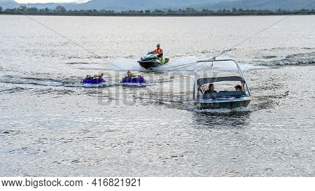 Mackay, Queensland, Australia - April 2021: Power Boat Towing Tubers With Man Riding Jet Ski Behind 