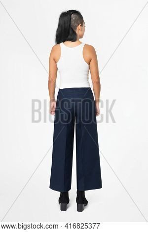 Cool woman in white tank top and black a-line pants street fashion rear view