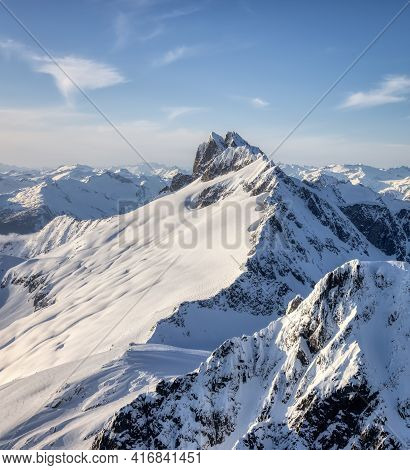 Aerial View From Airplane Of Blue Snow Covered Canadian Mountain Landscape In Winter. Bright Sunny S