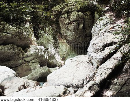 Embossed Rocky Area With Green Plants Hanging From It And Trees At The Top. Agur Gorge