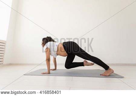 Young Flexible Pregnant Woman Doing Gymnastics On Rug On The Floor On White Background. The Concept 