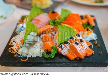 Mixed Sliced Fish Sashimi On Ice In Black Bowl. Sashimi Salmon Tuna Hamachi Prawn And Surf Calm Set,