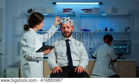 Patient Wearing Brainwave Scanning Headset Discussing With Neurological Researcher