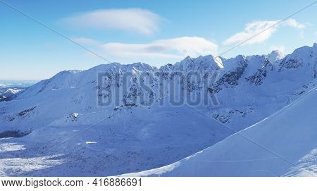 Picturesque View Of The Snow-covered Mountains Against A Blue Cloudy Sky During The Winter Season Wi