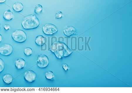 Drops Of Gel With Hyaluronic Acid In The Form Of A Smear Of Glossy Texture On A Blue Background.