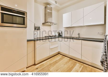 Modern Home Kitchen Corner Interior Design With White Cupboards And Cabinets And Steel Hood Over Sto