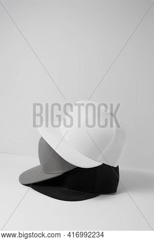 Set Of Three Blank Monochrome White, Gray And Black Baseball Cap Isolated Over Light Background. Emp