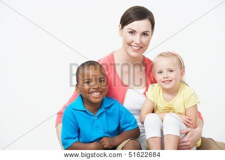 Studio Portrait Of Female Pre School Teacher With Pupils