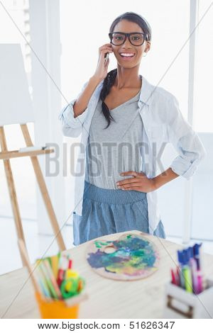 Cheerful pretty artist in bright room having a phone call