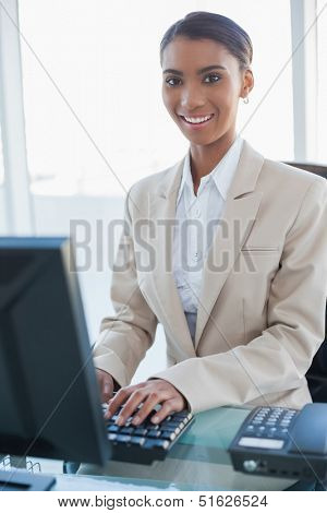 Cheerful businesswoman working on her computer in bright office