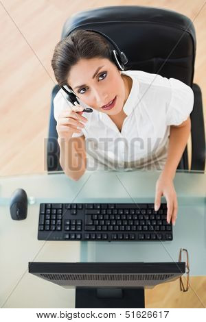 Serious call center agent looking at camera while on a call in her workplace