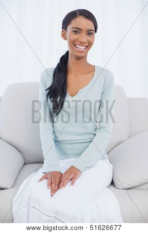 Smiling attractive woman sitting on cosy sofa in bright living room