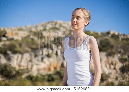 Woman with eyes closed enjoying the sun against mountain and blue sky