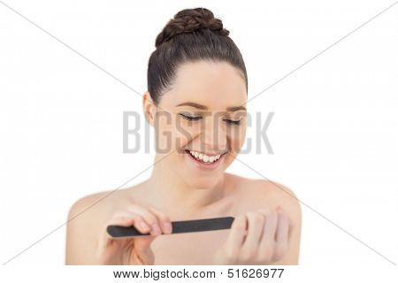 Smiling pretty model filing her fingernails while posing on white background