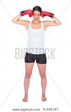 Serious young model with boxing gloves posing on white background