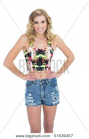 Pleased retro blonde model posing with hands on the hips on white background