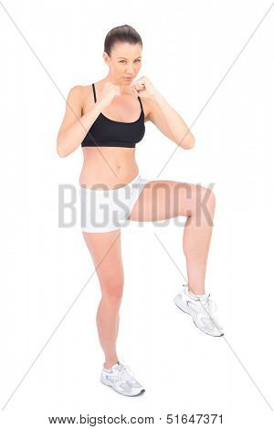 Serious woman in sportswear boxing on white background